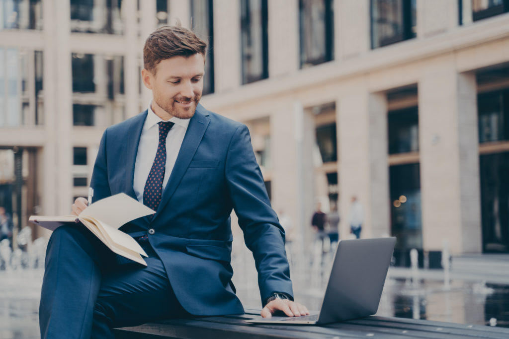 Professional young man company employee in blue formal suit doing research on laptop about pay-per-call